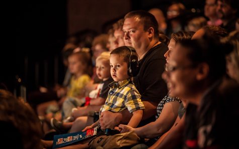 Child on lap with headphones in audience at Children's Theatre Company